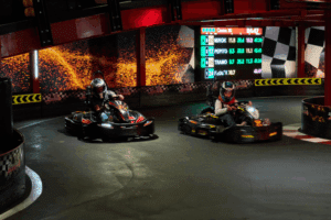 Zwei Karts mit Fahrer auf der Strecke in einer Kurve.
