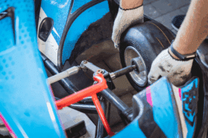 Mitarbeiterwechselt Reifen an blauem Kart.