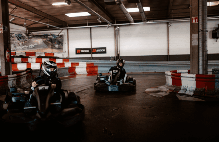 Mehrere Karts im Wettkampf durchfahren eine Kurve der Rennbahn im Kartcenter Cologne beim Kartfahren Köln.